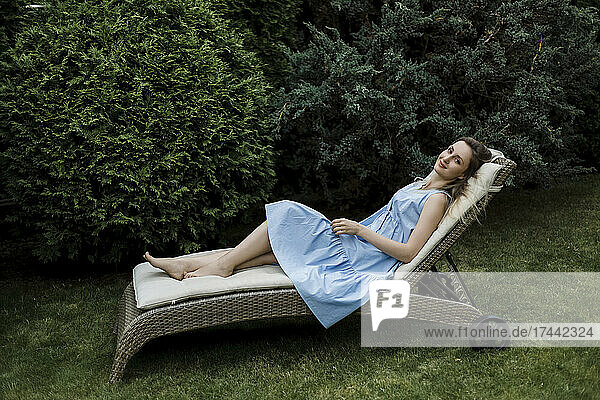 Frau entspannt sich auf Liegestuhl neben Pflanzen im Garten