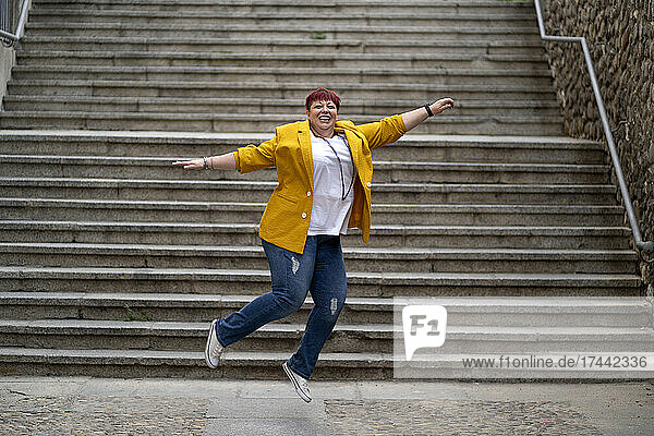 Carefree mature woman jumping in front of steps