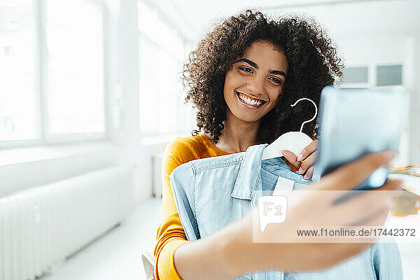 Smiling woman with shirt taking selfie through mobile phone