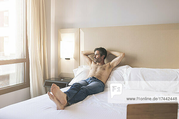 Shirtless man relaxing in hotel room