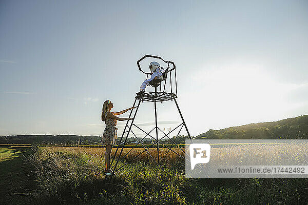 Mother looking at son while standing on lookout tower during sunset