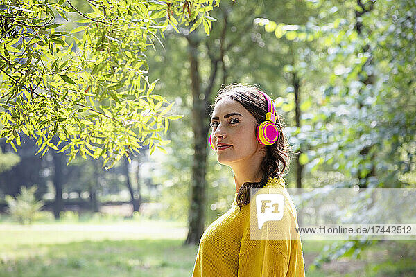 Woman listening music through wireless headphones at park