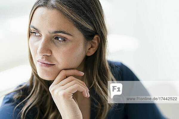 Thoughtful businesswoman with hand on chin in office