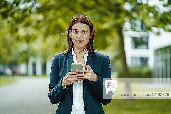 Female freelancer holding mobile phone at park