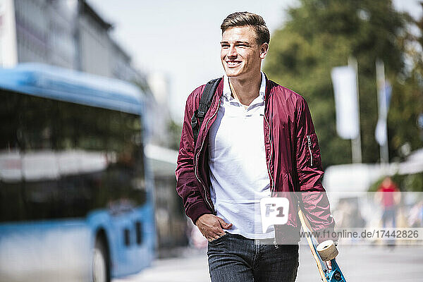 Smiling man walking with hand in pocket