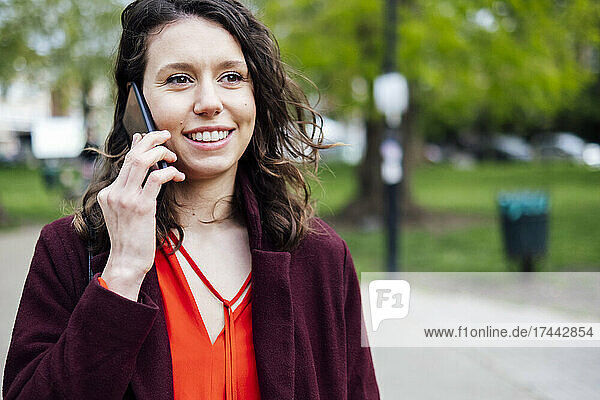 Smiling woman talking on mobile phone at park