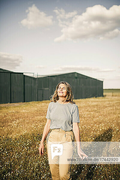 Smiling mature woman with eyes closed at agricultural field