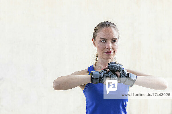 Female athlete with sports glove gesturing in front of wall