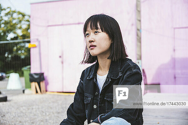 Thoughtful teenage girl sitting on footpath