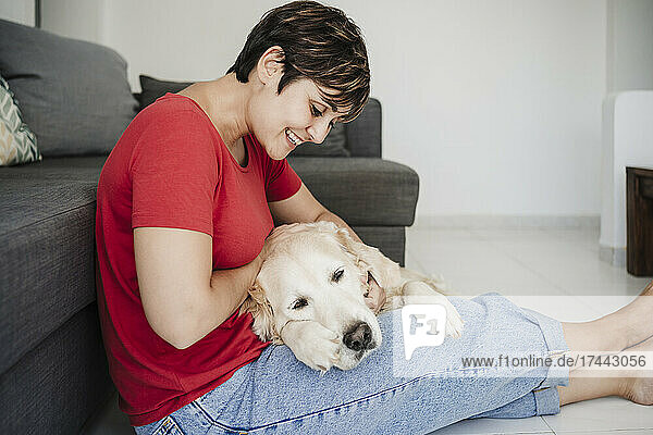 Smiling woman sitting with Golden retriever at home