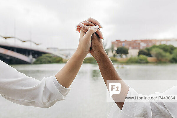 Girlfriends holding hands by lake
