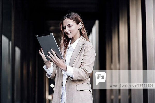 Young businesswoman using digital tablet at corridor