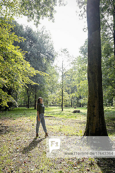 Young woman walking toward tree at park
