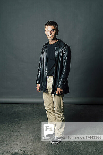 Young confident man wearing leather jacket at studio