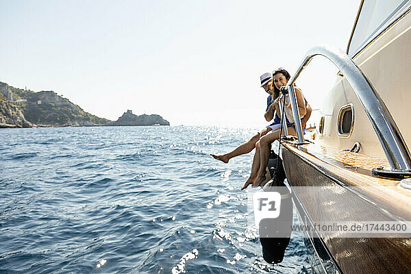 Ein Paar mittleren Alters sitzt an einem sonnigen Tag am Rand eines Motorboots