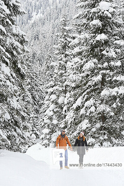 Man and woman holding hands while walking on snow