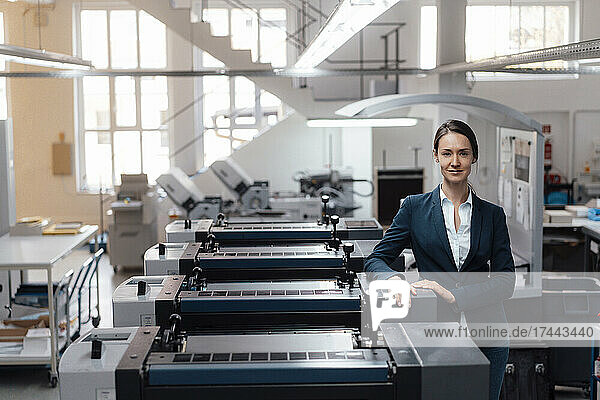 Female business professional standing by industrial equipment
