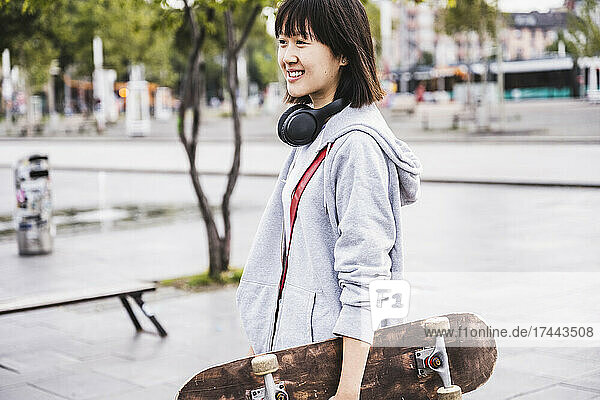 Female teenager with skateboard on footpath
