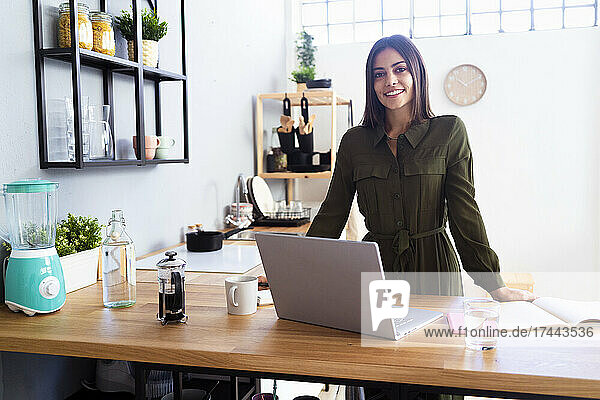 Smiling female freelancer standing in kitchen at home