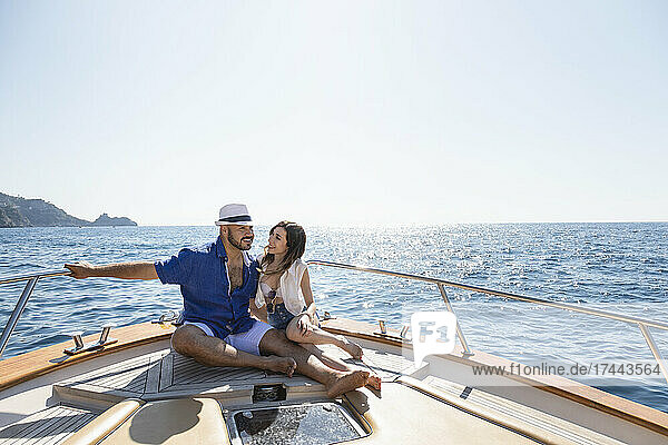 Lächelndes Paar sitzt an einem sonnigen Tag gemeinsam im Motorboot