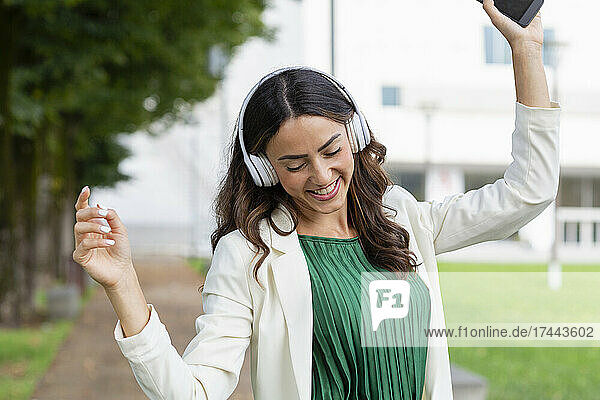 Carefree woman dancing while listening music through wireless headphones