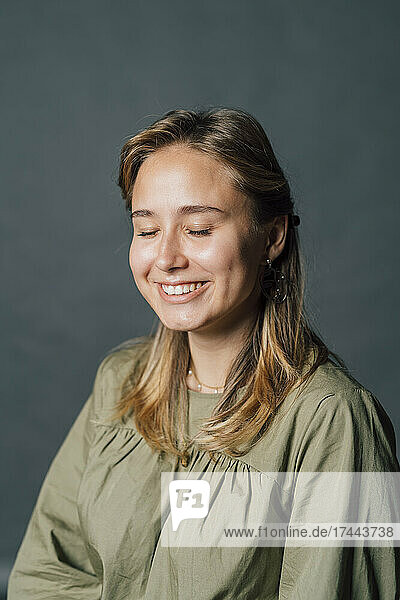Smiling young woman with eyes closed in studio