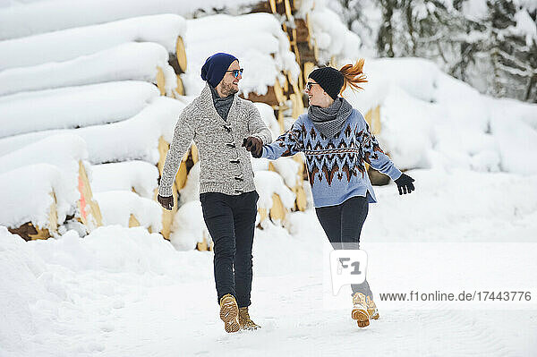 Mid adult couple in warm clothing holding hands while walking on snow