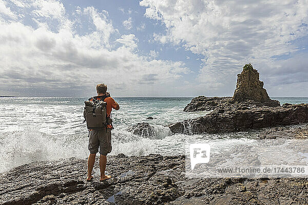 Male tourist photographing Cathedral Rocks at Jones Beach  Australia