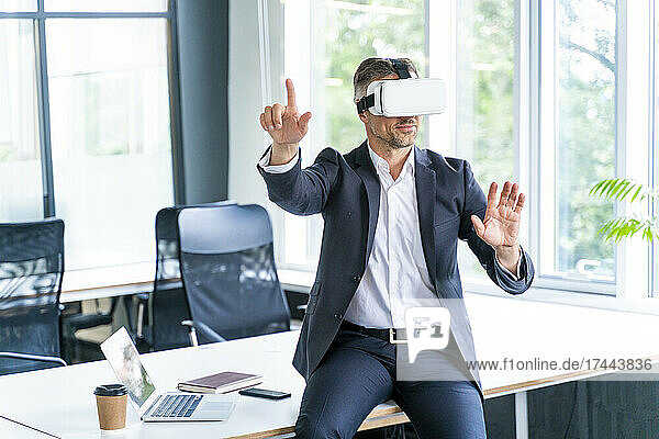Male business professional wearing virtual reality headset gesturing in office
