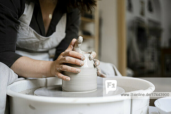 Craftswoman molding clay on pottery wheel in workshop