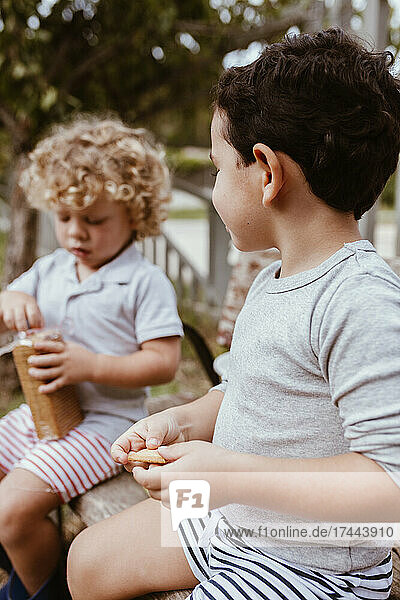 Boys eating biscuits while sitting on bench