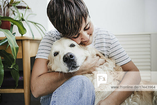 Mid adult woman embracing dog at home