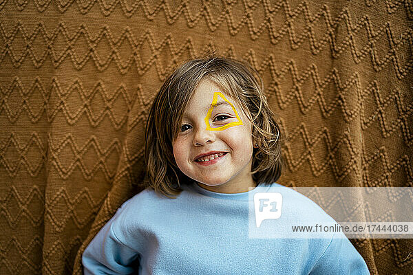 Smiling girl with face paint standing in front of brown cloth