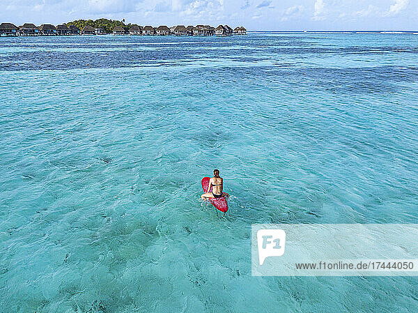 Woman sitting on surfboard at Huraa island  Maldives