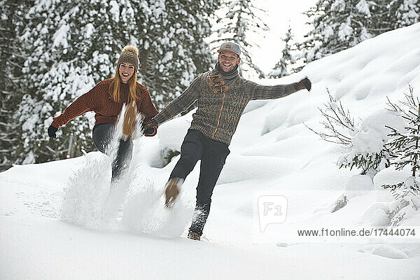 Playful couple kicking snow during winter