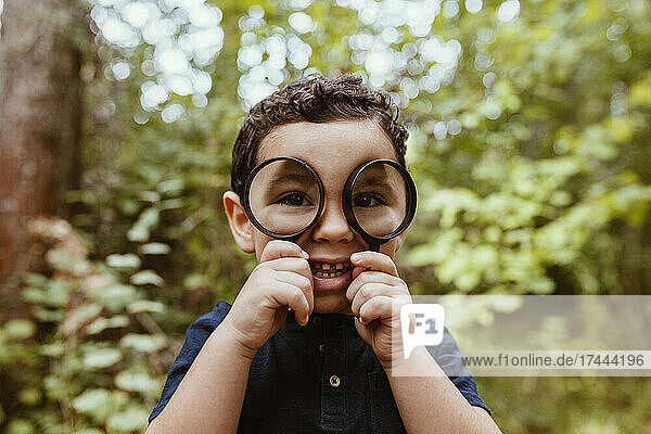 Playful boy looking through magnifying glass