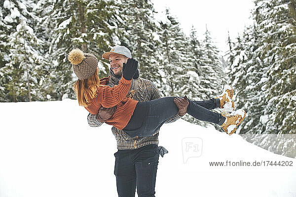 Man carrying woman while walking on snow