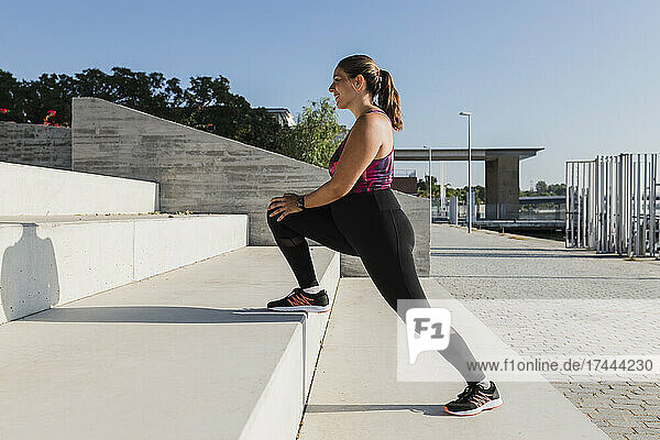 Young sportswoman doing stretching exercise on steps
