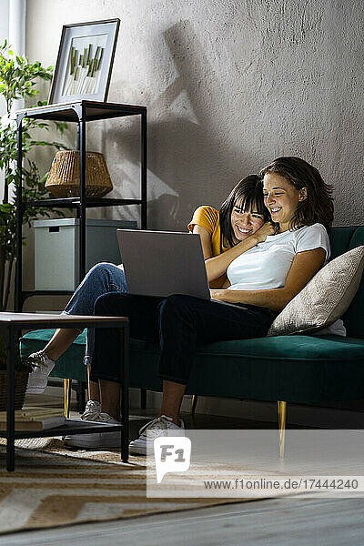 Happy lesbian couple using laptop while sitting at home