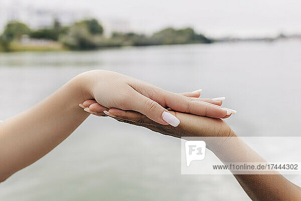Women touching hands by lake
