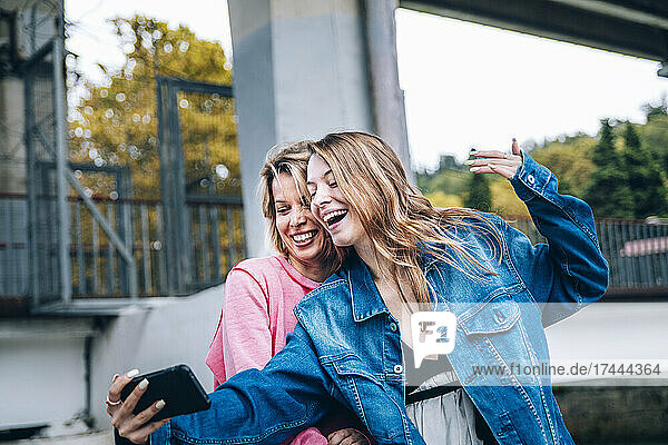 Teenage girl taking selfie with woman through smart phone