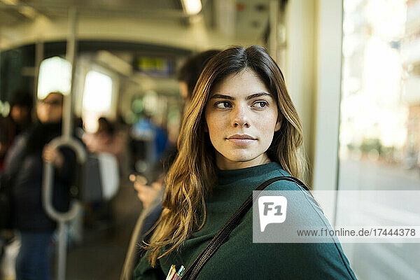 Young woman looking through window while travelling in tram