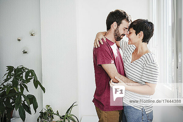 Man and woman with eyes closed embracing each other at home