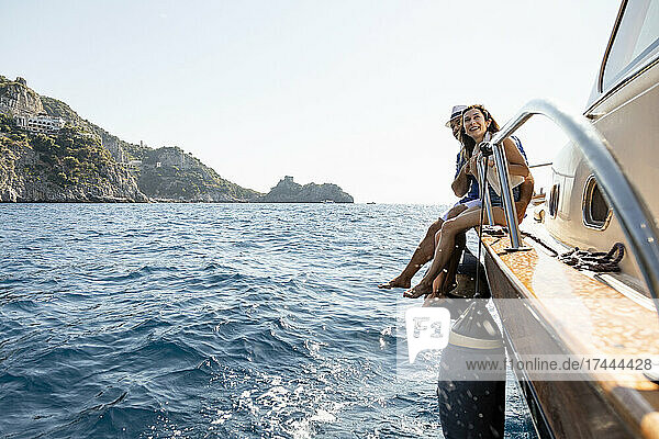 Happy couple sitting at motorboat's edge in Amalfi Coast  Italy