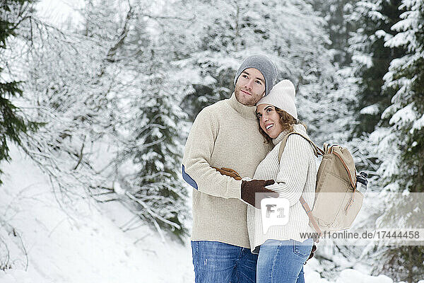 Couple embracing while standing in forest during winter