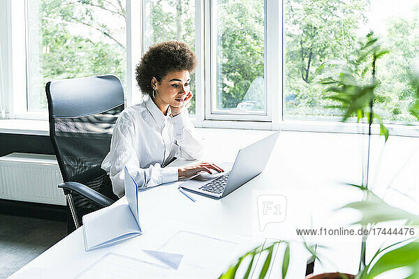 Female business professional using laptop in office