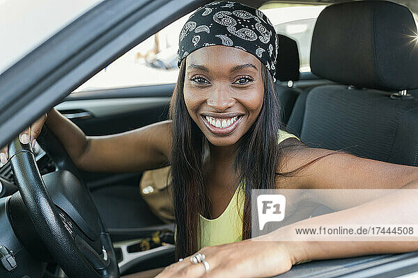 Fröhliche Frau mit Kopftuch sitzt im Auto