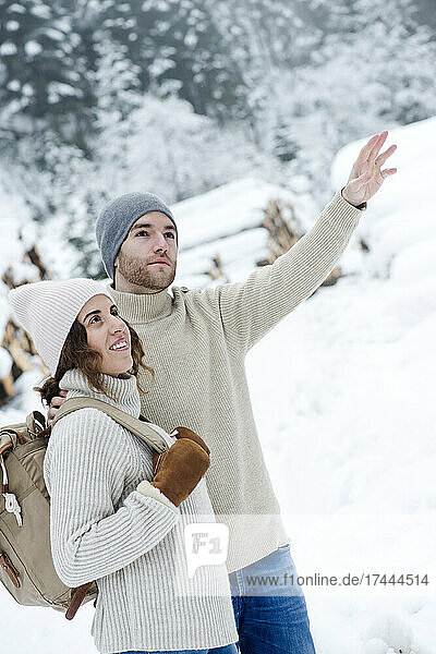 Boyfriend pointing while hiking with girlfriend during winter