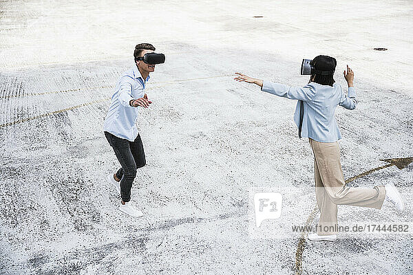 Male and female colleagues using virtual reality headset on rooftop