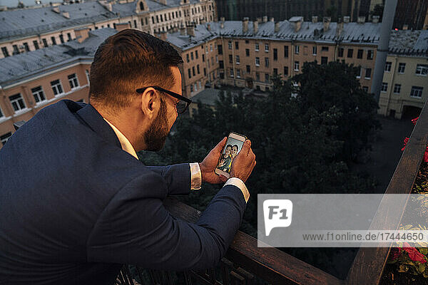 Businessman doing video call while leaning on railing during sunset